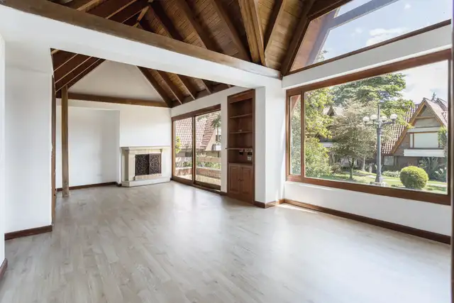 Large living room with a wood-lined ceiling and full-height windows looking onto trees